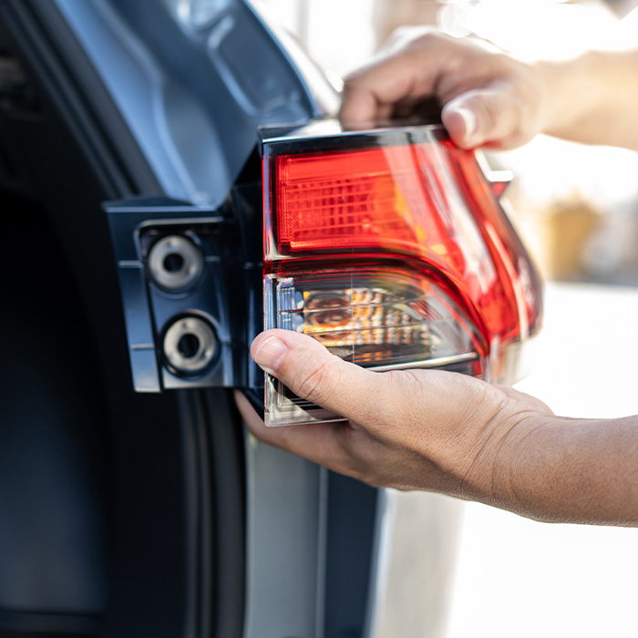 someone inspecting and tail-light for a car