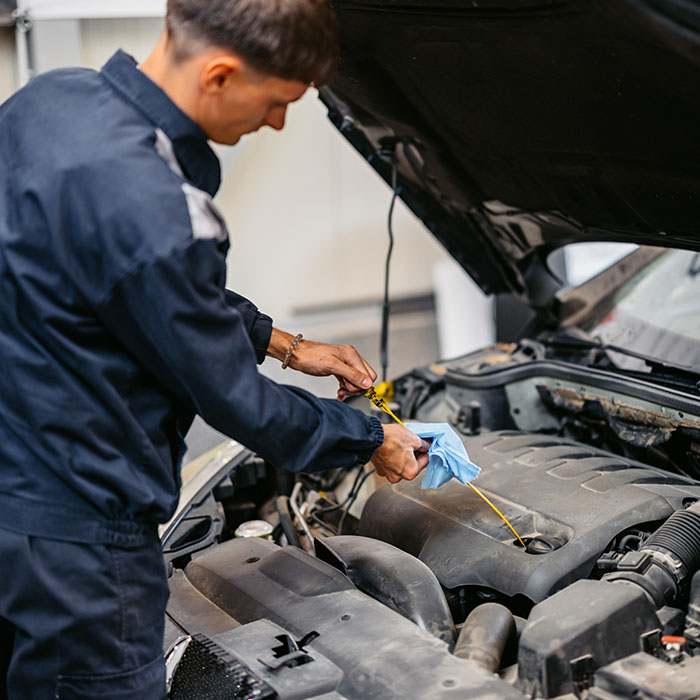 man inspecting a dipstick for a car engine