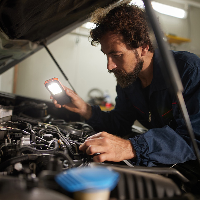 man inspecting an engine for a car